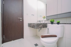 A bathroom with a toilet, sink, and a mirror. - Affordable Value Studio At Apartment Nine Residence (Jakarta)