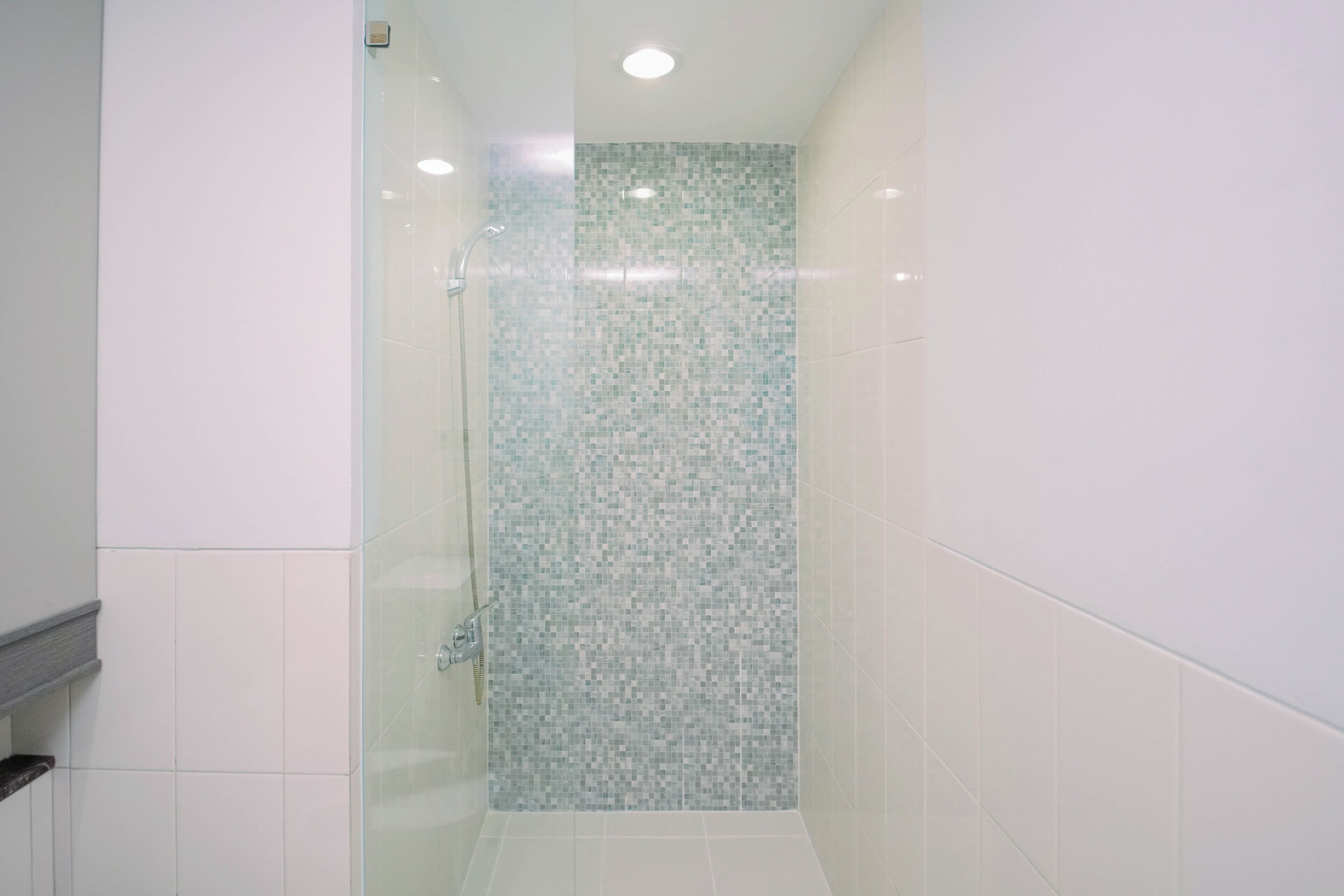 A modern bathroom with a glass shower enclosure, tiled walls, and a white floor.