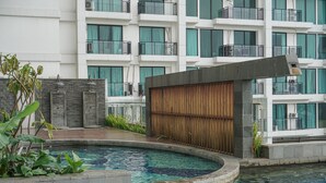 A modern hotel with a swimming pool, a wooden deck, and a building with balconies and large windows. - Affordable Value Studio At Apartment Nine Residence (Jakarta)