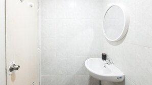 A bathroom with a white sink, a mirror, and a toilet. - Neat And Tidy Studio At Apartment Parkland Avenue (Tangerang)