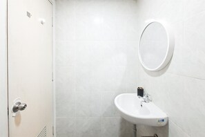 A bathroom with a white sink, a mirror, and a toilet. - Neat And Tidy Studio At Apartment Parkland Avenue (Tangerang)
