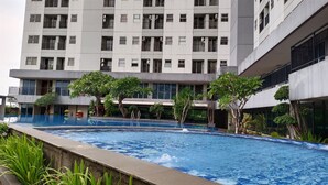A modern building with multiple balconies and a swimming pool area. - Neat And Tidy Studio At Apartment Parkland Avenue (Tangerang)