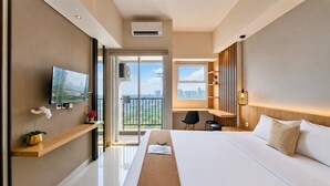 A modern hotel room with a large bed, a TV, a balcony with a city view, and a desk area. - Neat And Tidy Studio At Apartment Parkland Avenue (Tangerang)