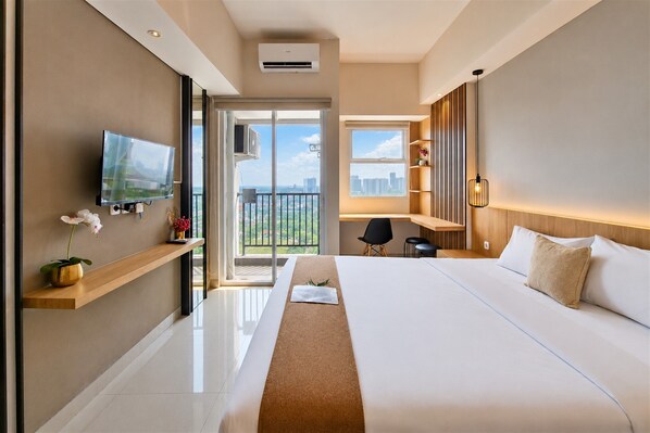 Een moderne hotelkamer met een groot bed, een televisie, een balkon met uitzicht op de stad en een bureau.