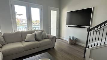 A living room with a sofa, a coffee table, and a TV mounted on the wall.