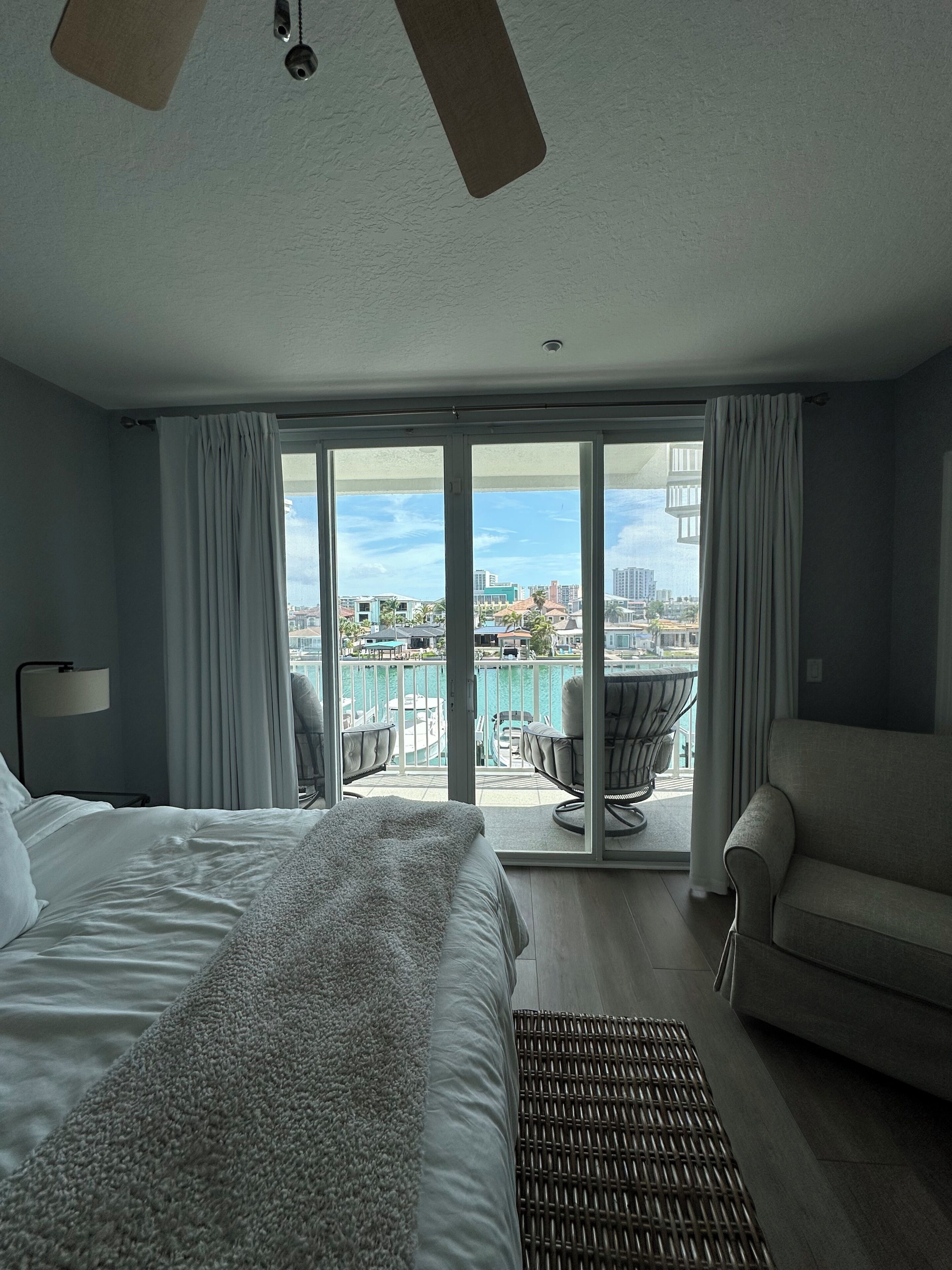 Ein Hotelzimmer mit Bett, einer Sitzecke, einem Balkon mit Stadtblick und einem Deckenventilator.