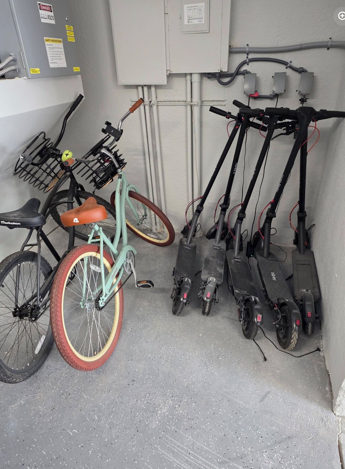Une pièce utilitaire contenant des panneaux électriques, des tuyaux et un vélo équipé d’un panier.
