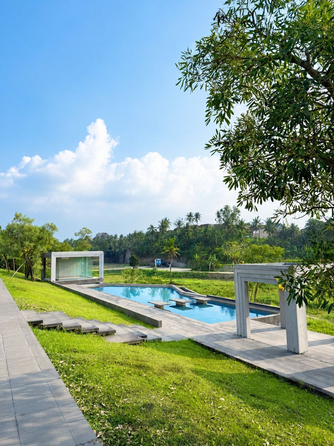 Piscina de diseño moderno, rodeada de un césped cuidado y un cielo despejado.