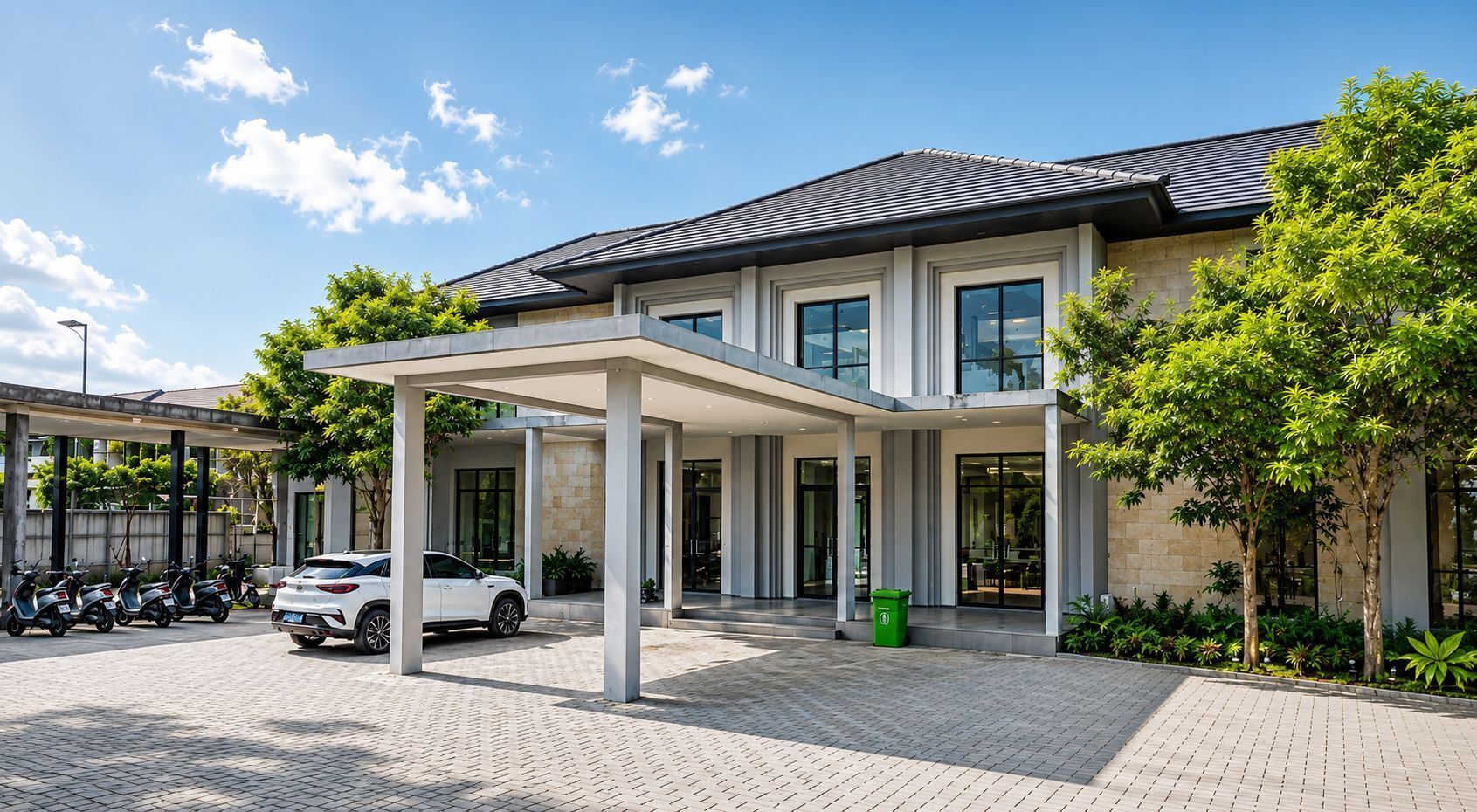 A modern building with a covered entrance, a paved driveway, and a white car parked in front.