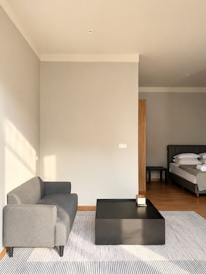Una sala de estar moderna con un sofá, una mesa de centro y una cama al fondo.