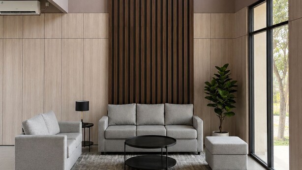 A modern living room with a high ceiling, a large window, and a vertical wooden panel wall. - Serene Modern 1BR at Sora Villa Cilegon (Cilegon)