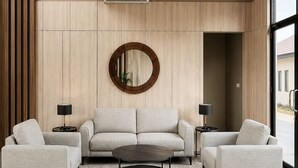 A modern living room with a sofa, two armchairs, a coffee table, and a round mirror on the wall. - Serene Modern 1BR at Sora Villa Cilegon (Cilegon)