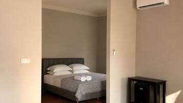 Un dormitorio con cama, mesita de noche y aire acondicionado.