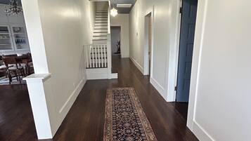 Un couloir avec un tapis à motifs, des murs blancs et un plafond foncé.