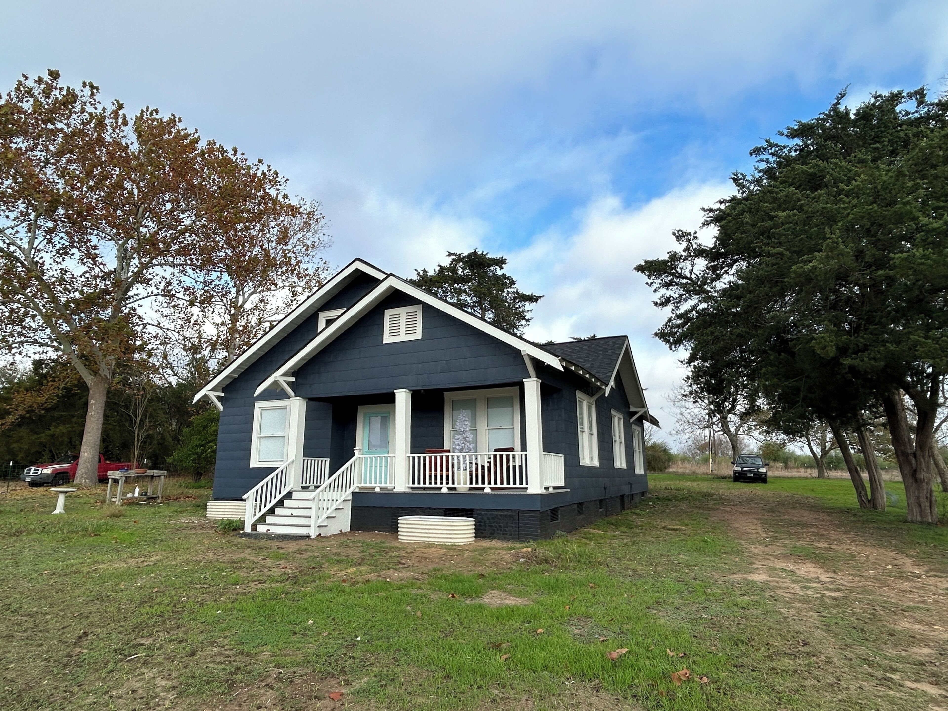 A two-story house with a front porch, a staircase, and a small garden area.