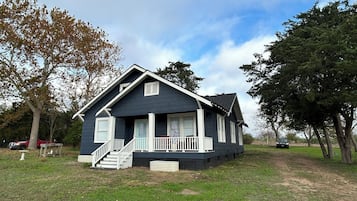 A two-story house with a front porch, a staircase, and a small garden area.