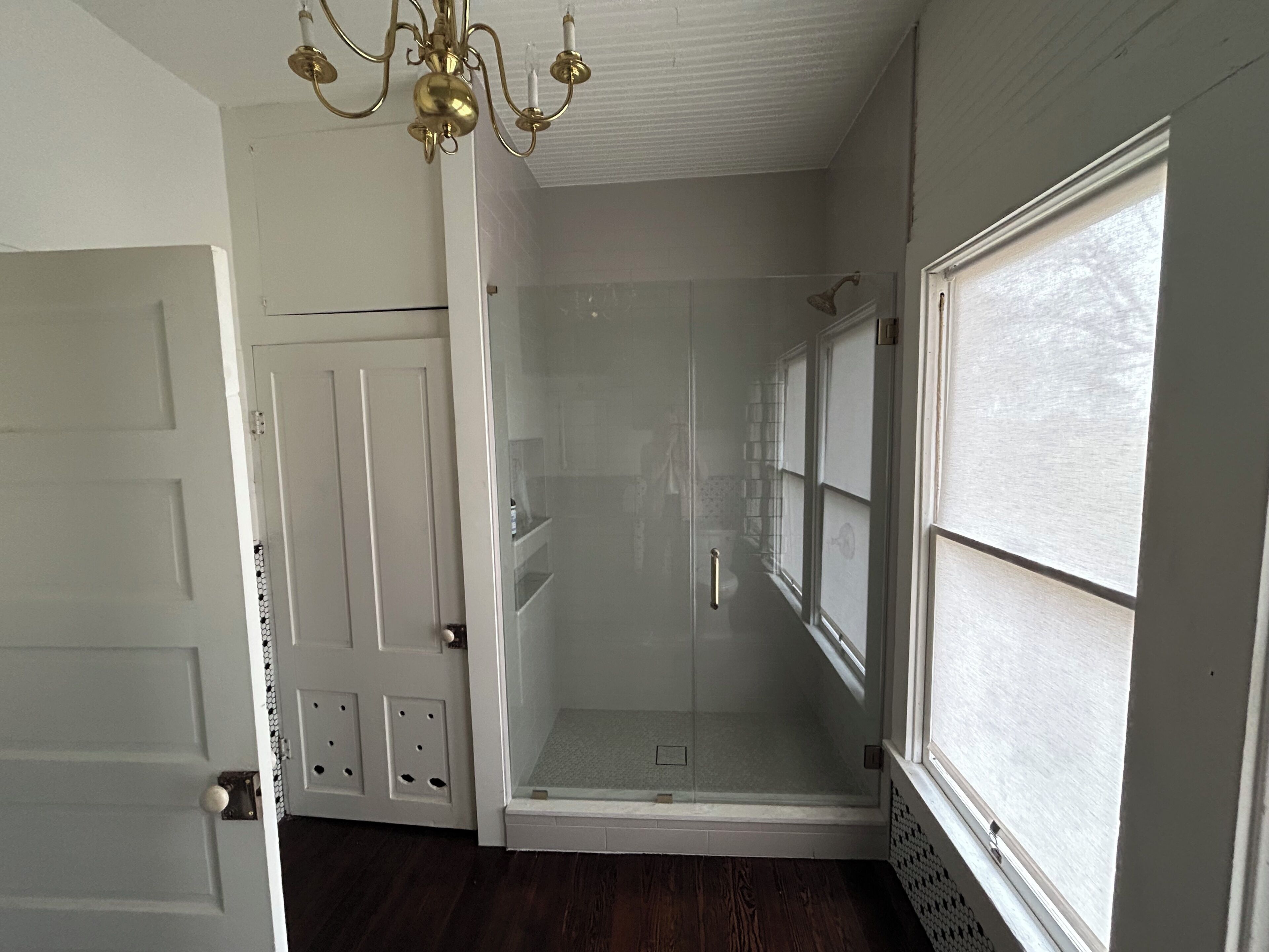 A room with a walk-in closet, a glass shower enclosure, and a large window.