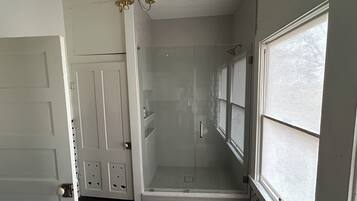 A room with a walk-in closet, a glass shower enclosure, and a large window.