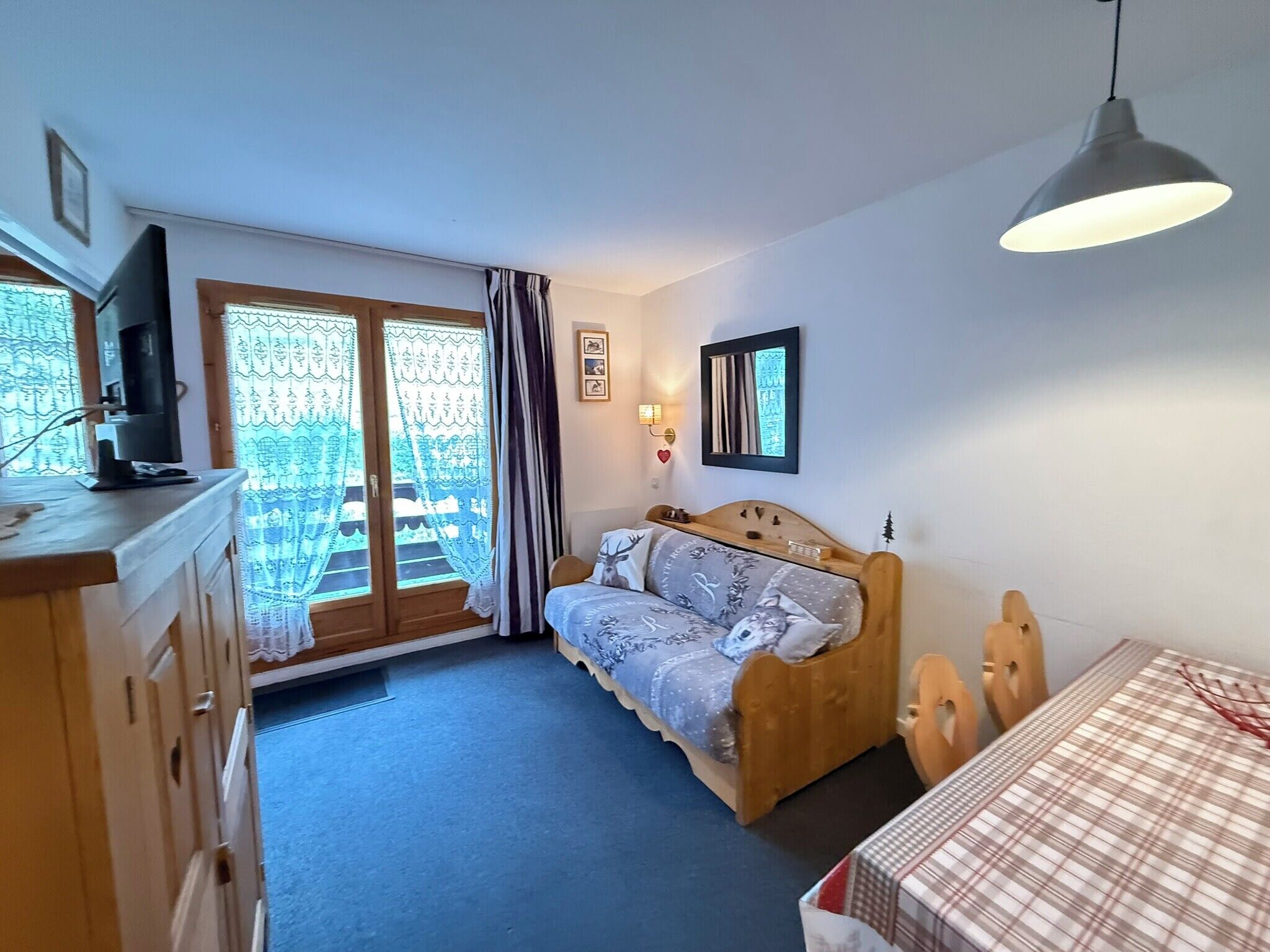 Ein Schlafzimmer mit einem Bett, einem Schreibtisch, einem Stuhl, einem Fernseher und einem Fenster mit Vorhängen.