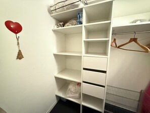 A white closet with multiple shelves and hanging space, a red heart-shaped balloon, and a small Christmas tree decoration. - Appart 4 pers • proche pistes• Piscine et sauna • Risoul (Risoul)