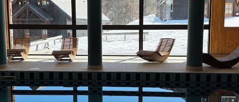 Un espace piscine avec des chaises en bois et une vue sur un paysage enneigé.