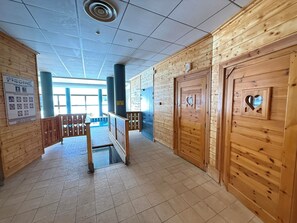 A hallway with wooden walls, a tiled floor, and a staircase leading to an upper level. - Appart 4 pers • proche pistes• Piscine et sauna • Risoul (Risoul)