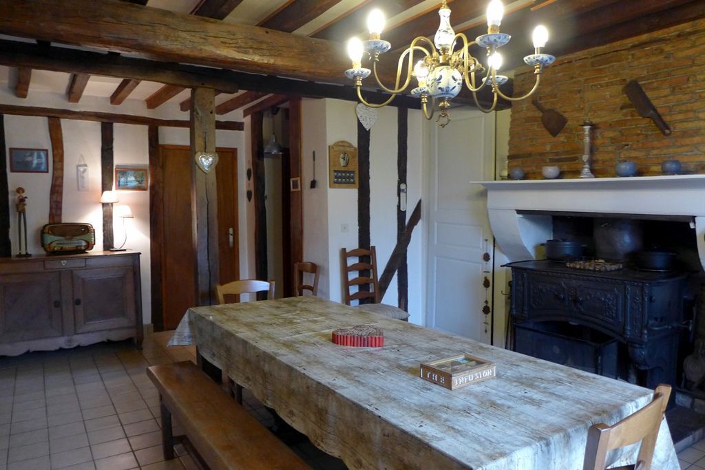 Un coin repas rustique avec une table en bois, des bancs et un lustre.