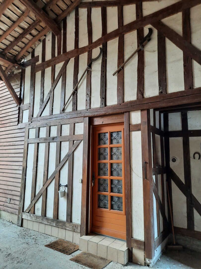 Un bâtiment à pans de bois, doté d’une porte en bois et d’une fenêtre à carreaux.