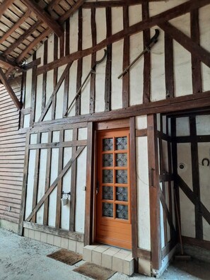 Edifício em estilo enxaimel com porta de madeira e janela com padrão quadriculado.