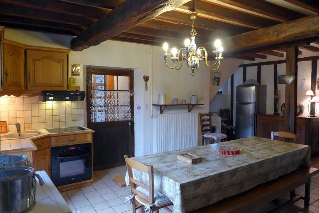A kitchen with wooden cabinets, a tiled backsplash, a chandelier, and a central island with chairs.