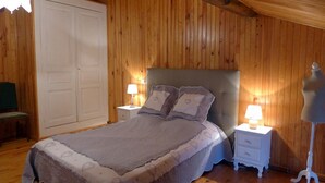 Ett sovrum med en säng, sängbord, en garderob och en lampa.