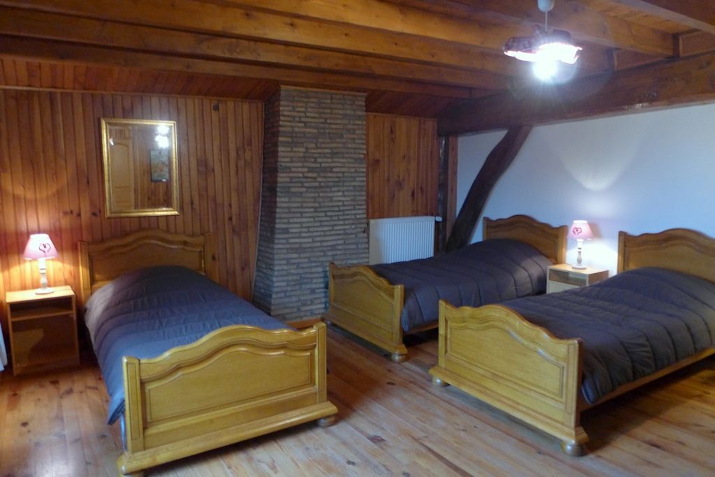 Une pièce avec deux lits en bois, une cheminée en briques et des murs en bois.