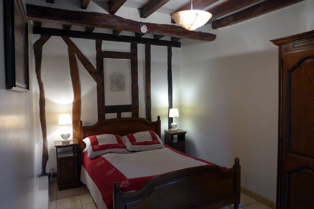 Una camera da letto con un letto di legno, due comodini con lampade, un soffitto in legno con travi a vista e un armadio in legno.