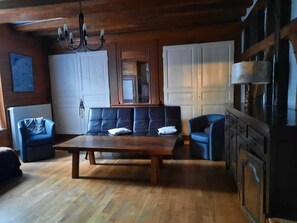 Ein großzügiger Wohnbereich mit einem Holztisch, Sofas und einer Küchenzeile mit Schränken.