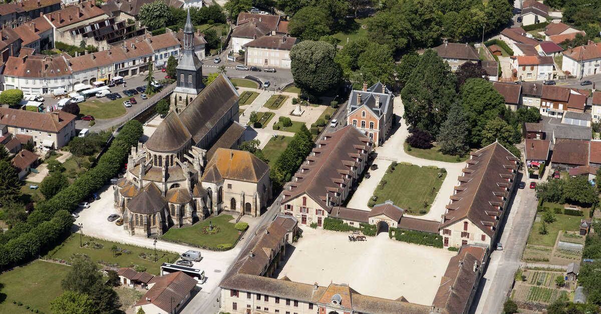 An aerial view of a town with a prominent church, residential buildings, and a large open square.