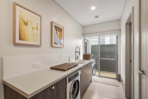 Een moderne keuken met een ingebouwde wasmachine, een spoelbak en een houten snijplank.