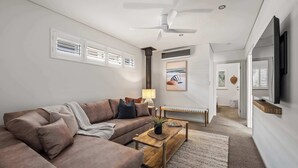 En moderne stue med en hjørnesofa, et sofabord, en lampe og et maleri på væggen.