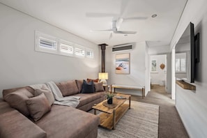 A modern living room with a sectional sofa, a coffee table, a lamp, and a painting on the wall. - Coastal Rhythms - A Sophisticated Seaside Retreat (Dunsborough)