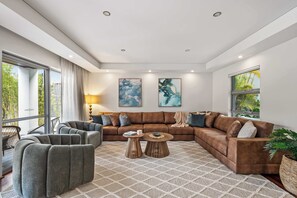 Een moderne woonkamer met een hoekbank, fauteuils, een salontafel en kunstwerken aan de muren.