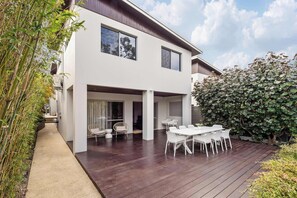 A modern two-story house with a covered patio area, outdoor seating, and a wooden deck. - Coastal Rhythms - A Sophisticated Seaside Retreat (Dunsborough)