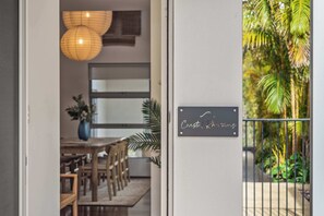 Un comedor con una mesa y sillas, una lámpara colgante y un cartel en la pared.