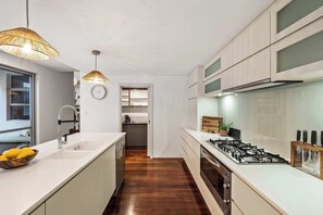 Una cocina moderna con una isla central, horno empotrado y estufa a gas.