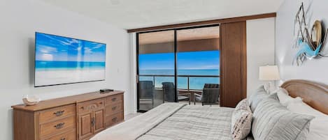 Une chambre à coucher avec un lit, une télévision, une commode et une vue sur l’océan.