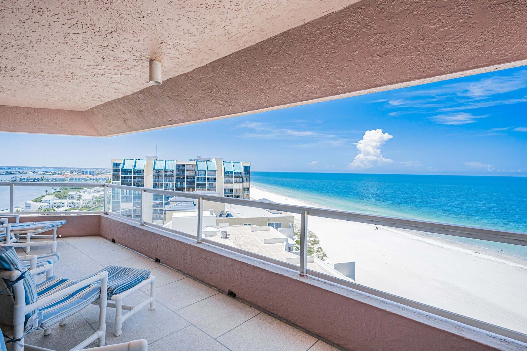 Ein Balkon mit Blick auf einen Strand und einen Gebäudekomplex.
