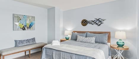 A bedroom with a bed, bedside tables, a bench, and wall art.