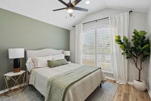 A bedroom with a bed, bedside tables, a ceiling fan, a window with blinds, and a potted plant. - Family Friendly 3-bedroom home in Mansfield For Long Term Living - FTW 25 mins (Mansfield)