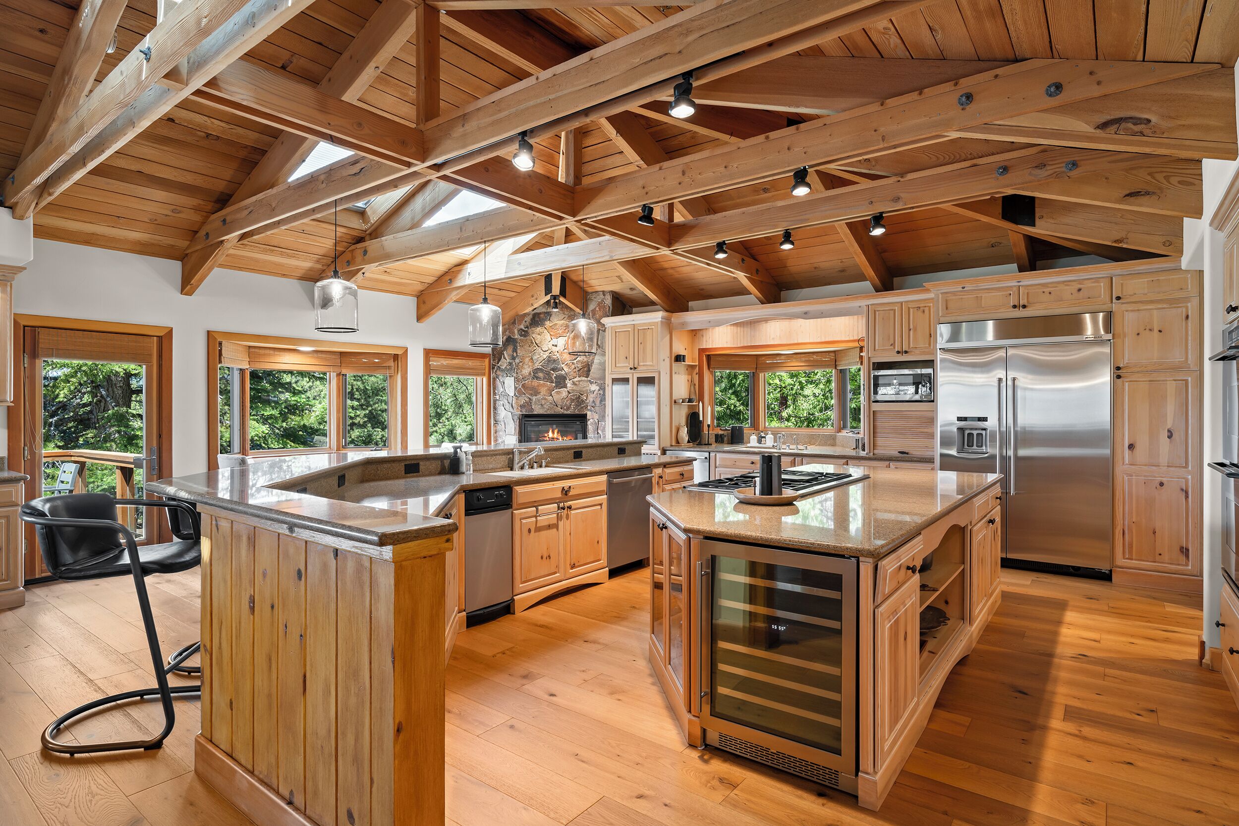 Une cuisine spacieuse avec des poutres en bois, de grandes fenêtres et des appareils électroménagers modernes.