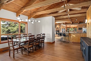 A spacious dining area with a wooden table and chairs, a stone fireplace, and a view of the outdoors. - Lake View home 4BR 5BA gym, game room, Large kitchen (Incline Village)