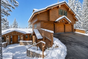 A wooden cabin with a stone foundation, a covered porch, and a garage. - Lake View home 4BR 5BA gym, game room, Large kitchen (Incline Village)