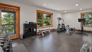 A gym with exercise equipment, a bench, and a window with a view of trees. - Lake View home 4BR 5BA gym, game room, Large kitchen (Incline Village)